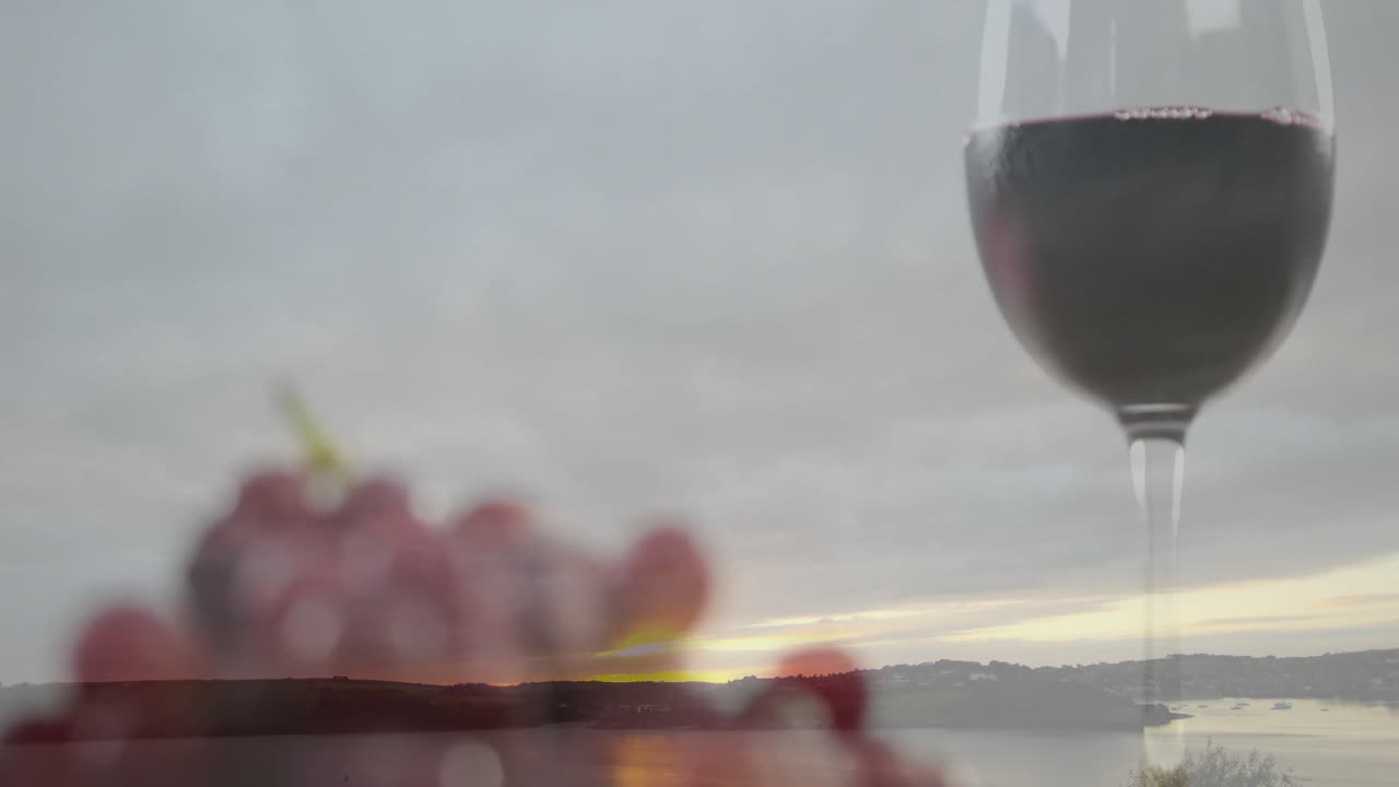 Animation of wine glass and grapes with serene lake landscape at sunset
