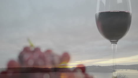 animation of wine glass and grapes with serene lake landscape at sunset