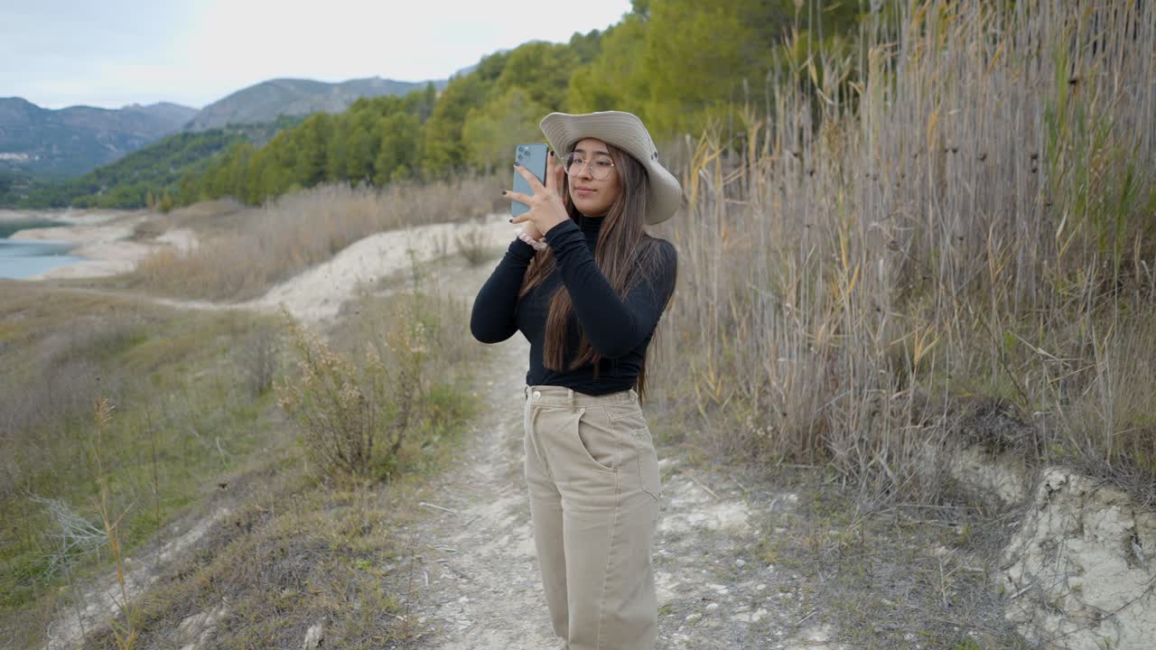 Donna che scatta una foto in riva al lago in montagna