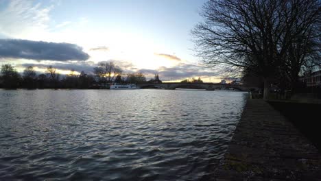 view of a sunset over the river thames with kew bridge at the distance