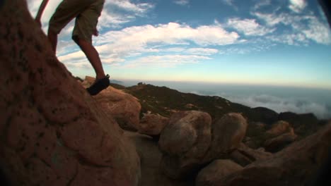 fisheye of a young hiker hopping from boulder to boulder in the santa barbara mountains