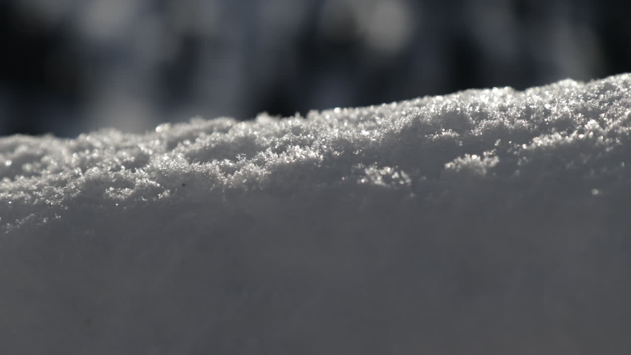 Detailed close-up of a luxury snow wall in Switzerland, with sparkling snow crystals glistening under bright sunlight on a clear winter day