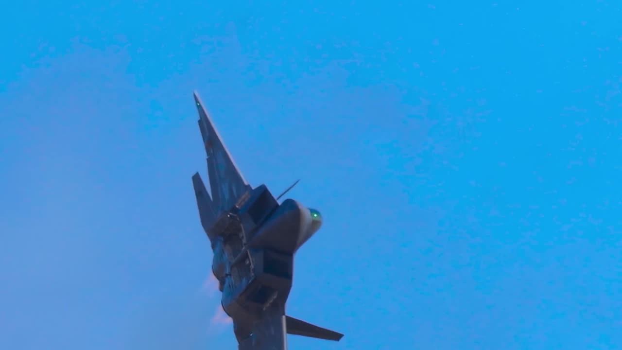 Un moderno aereo militare esegue una ripida ascesa verticale su uno sfondo di cielo blu brillante