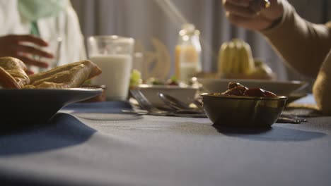 persona comiendo dátiles en la mesa familiar musulmana en casa preparada para la comida iftar rompiendo el ayuno diario durante el ramadán 2