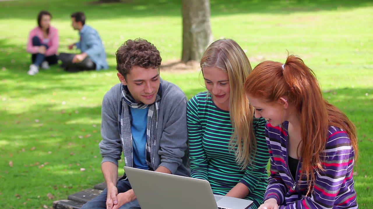 Three students looking at laptop together and laughing