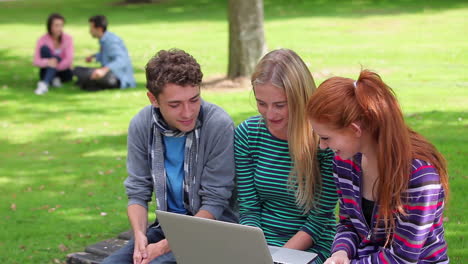 three students looking at laptop together and laughing