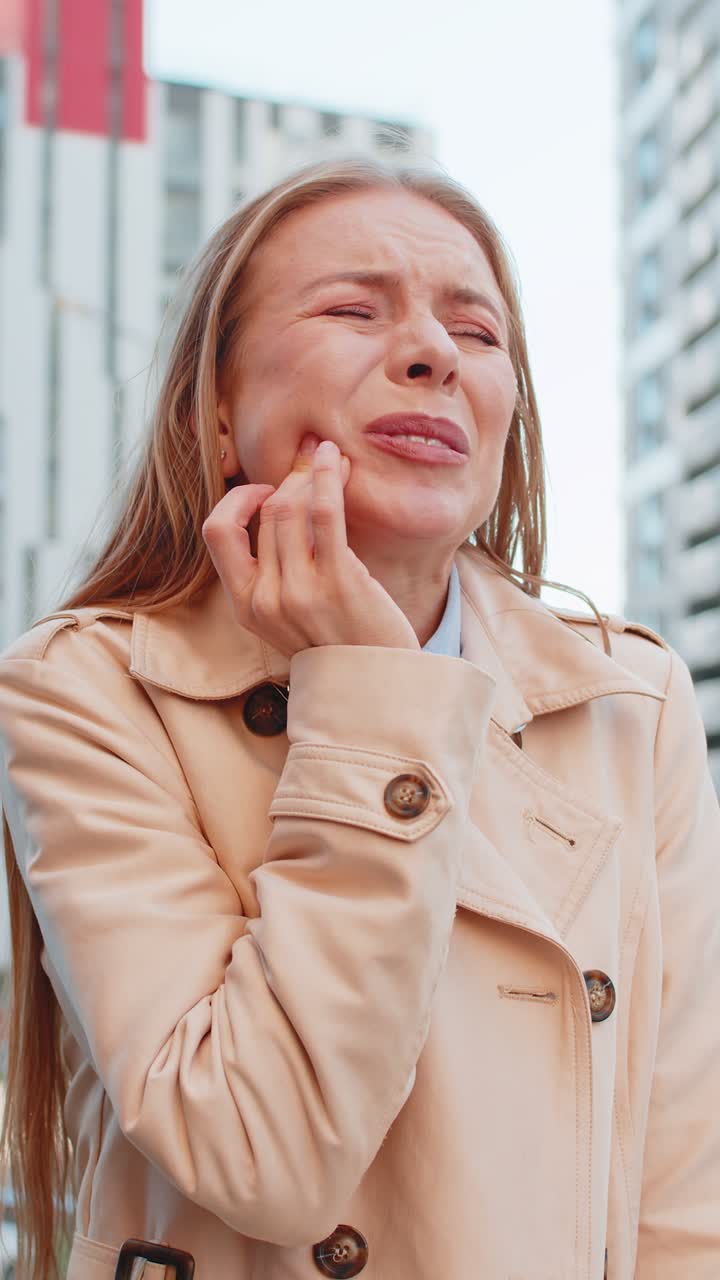 Mature caucasian businesswoman feeling toothache unpleasant symptoms suffering from pain on street