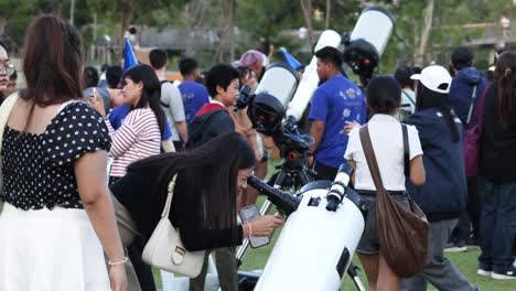 crowd observing through telescopes in a park