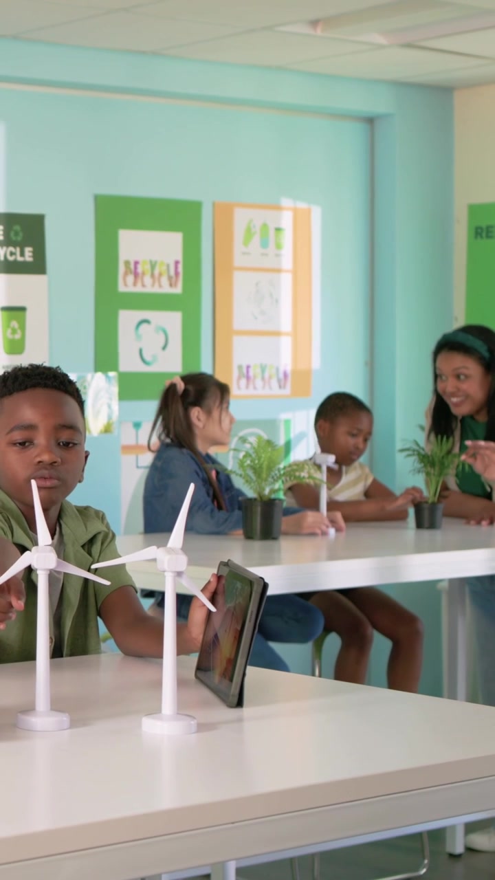 Vertical video: Reaching green-shirt boy spinning two turbines for plant lesson in lab, copy space