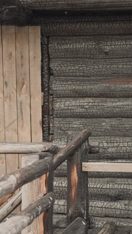 old log cabin with entrance door on porch. wooden stairs with platform and handrails. traditional style house built from burnt logs. medieval architecture