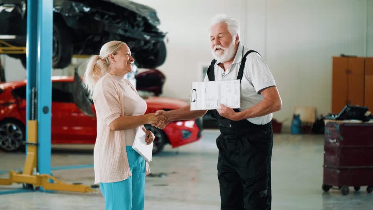 un agente de seguros satisfecho y un mecánico se dan la mano después de llegar a un acuerdo sobre cooperación conjunta