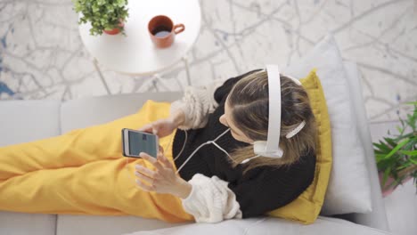 woman sitting on sofa at home listening to music with headphones. to relieve the stress of the day.