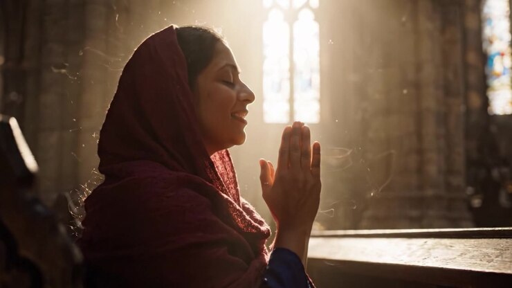 A contemplative moment captured in soft light, showcasing a woman's serene expression and devotion as she prays in a beautiful, ethereal setting filled with rich textures and warm shadows.