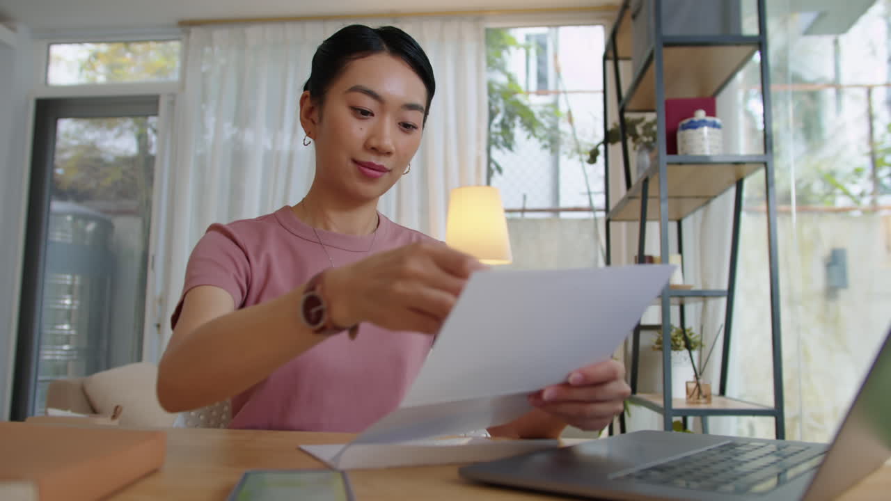 封筒からクレジットカードを取り出す若いアジア人女性