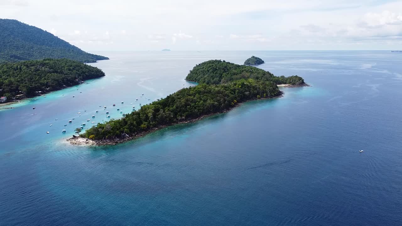 Rising aerial drone view over tropical island of Pulau Rubish with tour and fishing boats and idyllic blue and turquoise ocean water in Pulau Weh, Indonesia