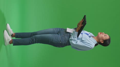 태블릿을 사용하는 아시아 사업가 여성의 전체 몸의 측면 뷰 스튜디오의 녹색 화면 배경에서 주변을 둘러보고