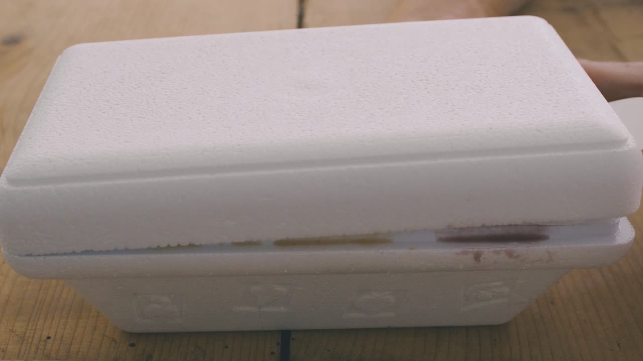 dos manos abren una tina de helado italiano artesanal con sabores de avellana, pistacho y fresa