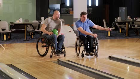 two young disabled men in wheelchairs playing bowling in the club