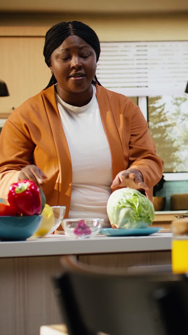 Video verticale: cuoca donna di colore che registra un video tutorial di cucina al bancone della cucina