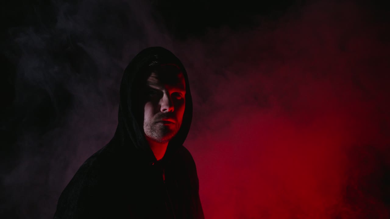 Dark hooded Man in dramatic red light and fog