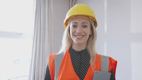 retrato de topógrafo con sombrero rígido y chaqueta de alta visibilidad con tableta digital realizando una inspección de la casa