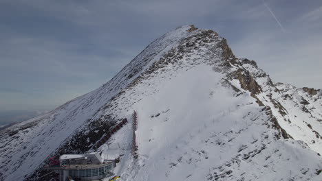 lift station on top of snowy mountain during sunny day in austria - aerial view