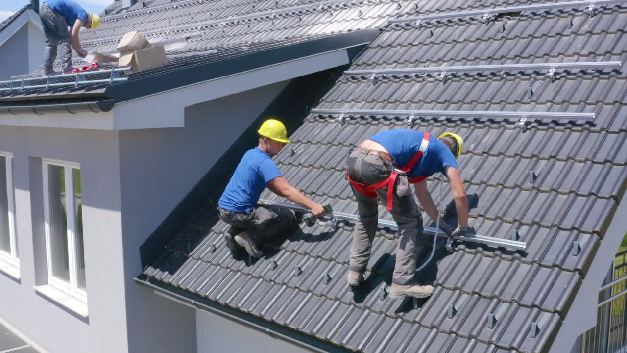Tradesman Install Solar Panels On Roof Of Suburban House