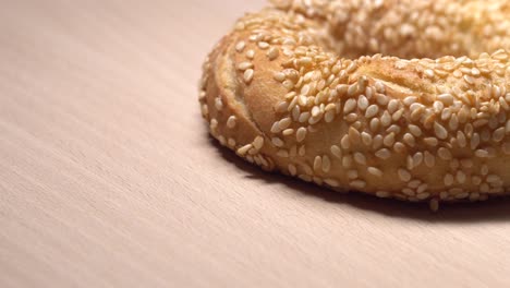 fresh bagels with sesame seeds in rotation. on wooden cutting board. extreme closeup.