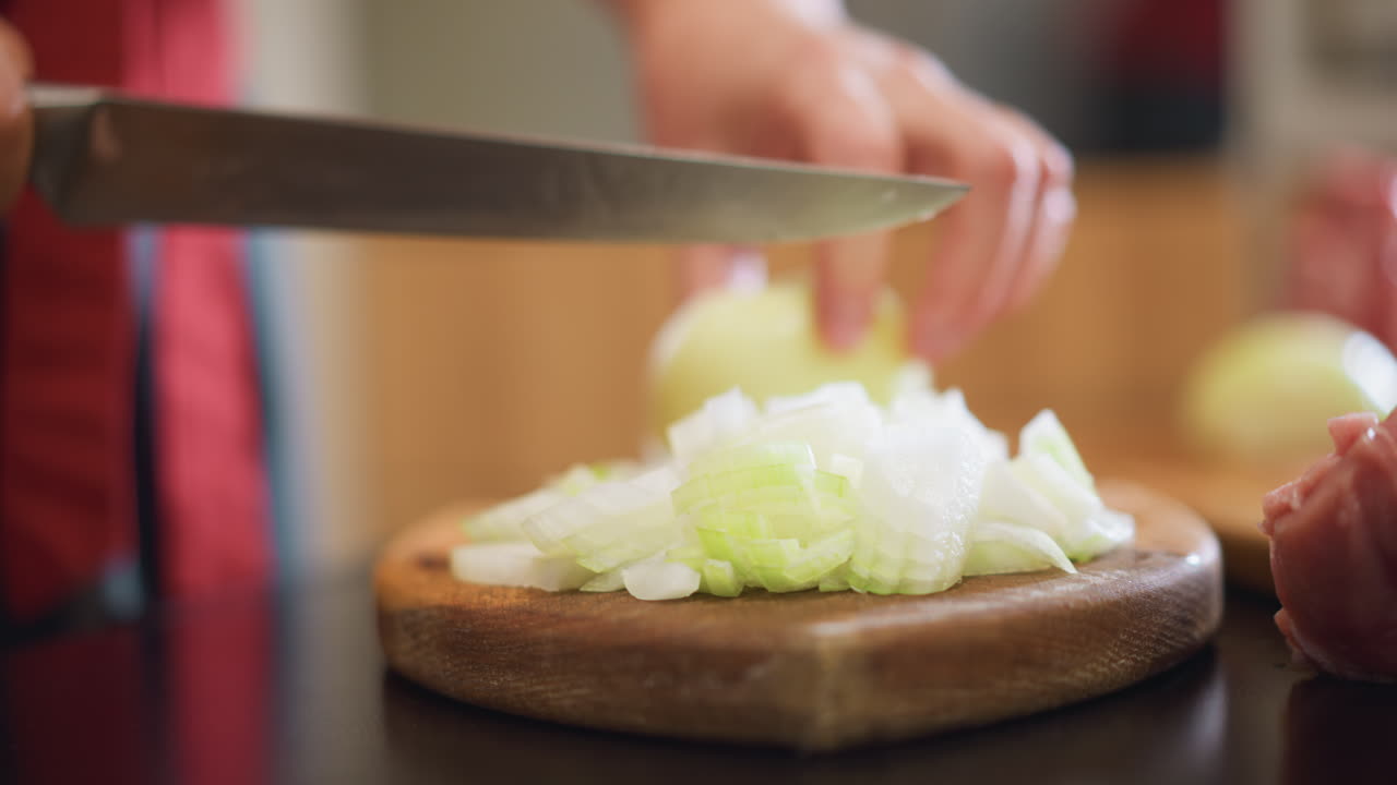 Onion and meat prep on wooden board, home chef preparing hearty family dinner, raw protein beside diced onion, focused knife motion, warm homestyle cooking atmosphere and aromatic seasoning