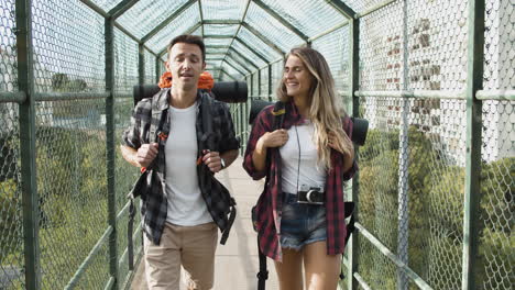 Couple-of-backpackers-walking-on-bridge-from-city