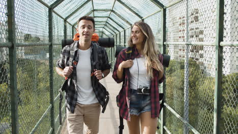 couple of backpackers walking on bridge from city