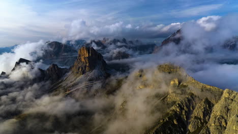 Vista-Aérea-De-Hermosas-Montañas-Iluminadas-Por-El-Amanecer,-Cubiertas-De-Espesa-Niebla-En-Dolomitas,-Italia