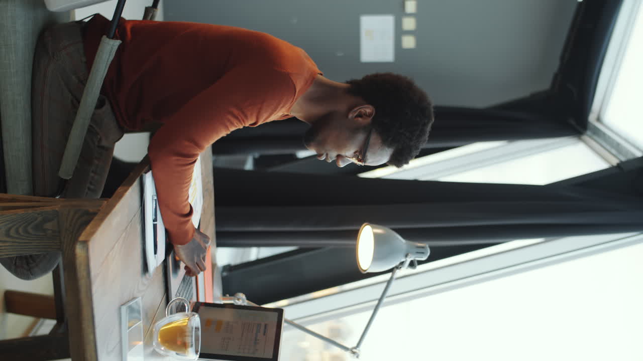 African American Office Worker Using Laptop and Taking Notes