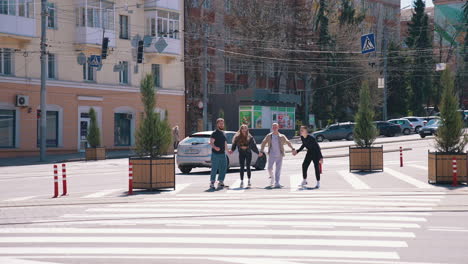 teenagers in the city street in sunny day. young people jumping together holding hands on the urban background near the road. happy friends outdoors.