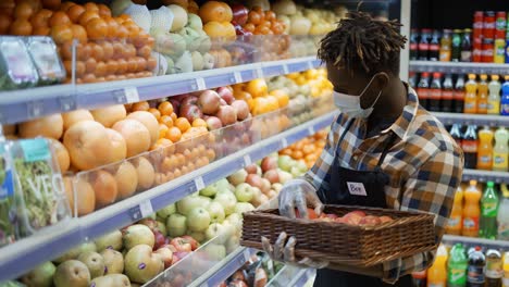 african american worker arranging storage racks in fruit department