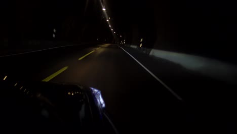 shot outside a blue nissan driving in a norwegian tunnel crossing a lane with mysterious lights on the ceiling