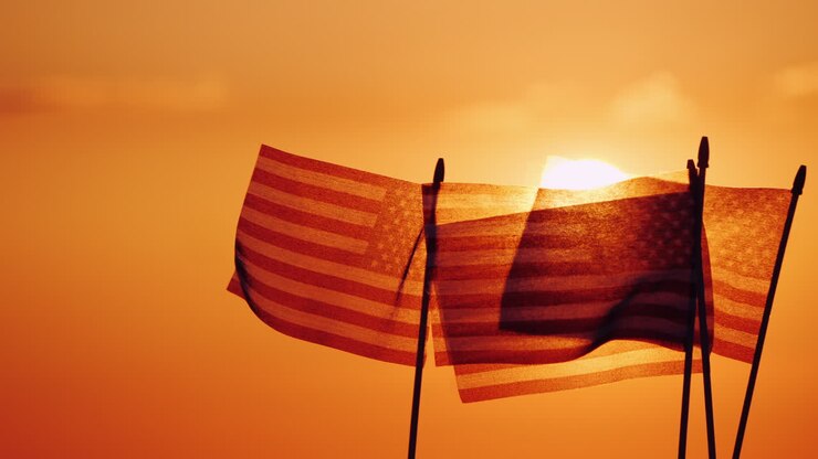 Several American Flags Against The Setting Sun And Orange Sky