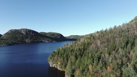 Hildremsvatnet,-Trondelag-County,-Norway---Calm-Blue-Waters-Enveloped-by-Lush-Greenery,-With-a-Distant-Mountain-Range-Completing-the-Tranquil-Panorama---Aerial-Drone-Shot