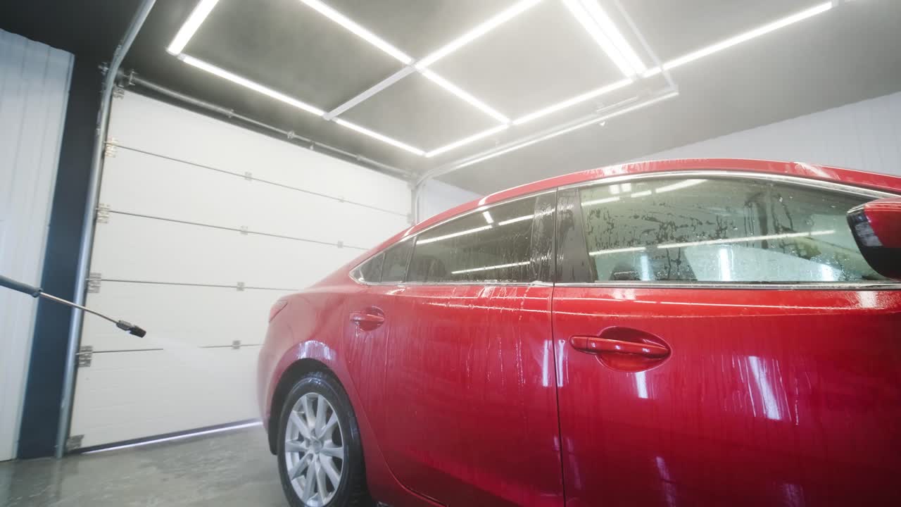 lavado de automóviles limpieza con espuma y agua a alta presión. coche rojo