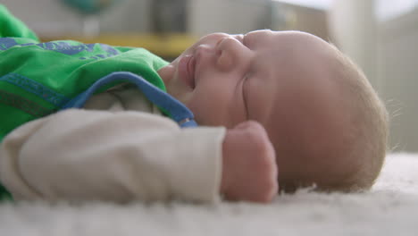 closeup shot of a baby smiling and stretching while sleeping on a carpet