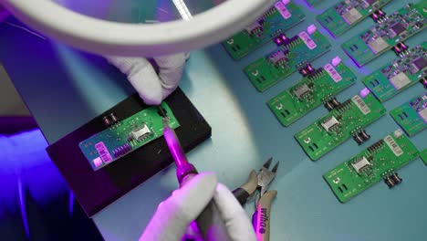 close-up of a person soldering elements of a base plate of an electronic device