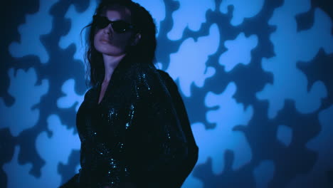 woman in sequin dress and sunglasses under blue light