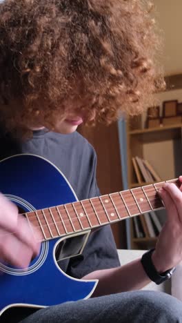 a young curly red-haired guy is learning to play the guitar. a talented guitarist plays a calm melody. hobby