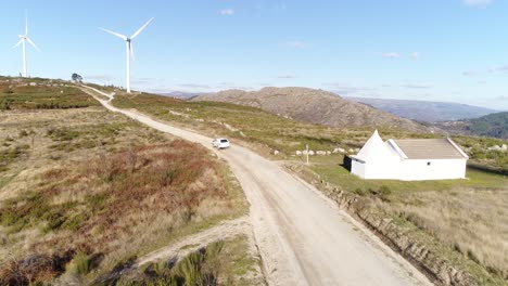 Auto-Unterwegs-Auf-Bergstraße-Mit-Windrad-Luftaufnahme