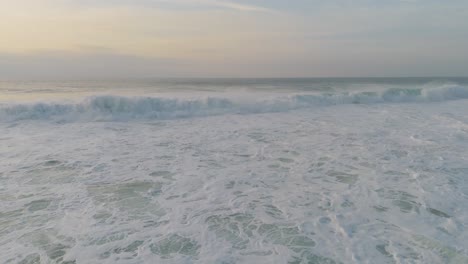 Vista-De-Drones-Sobre-Las-Olas-Del-Océano-Aplastando-Y-Haciendo-Espuma-Al-Atardecer