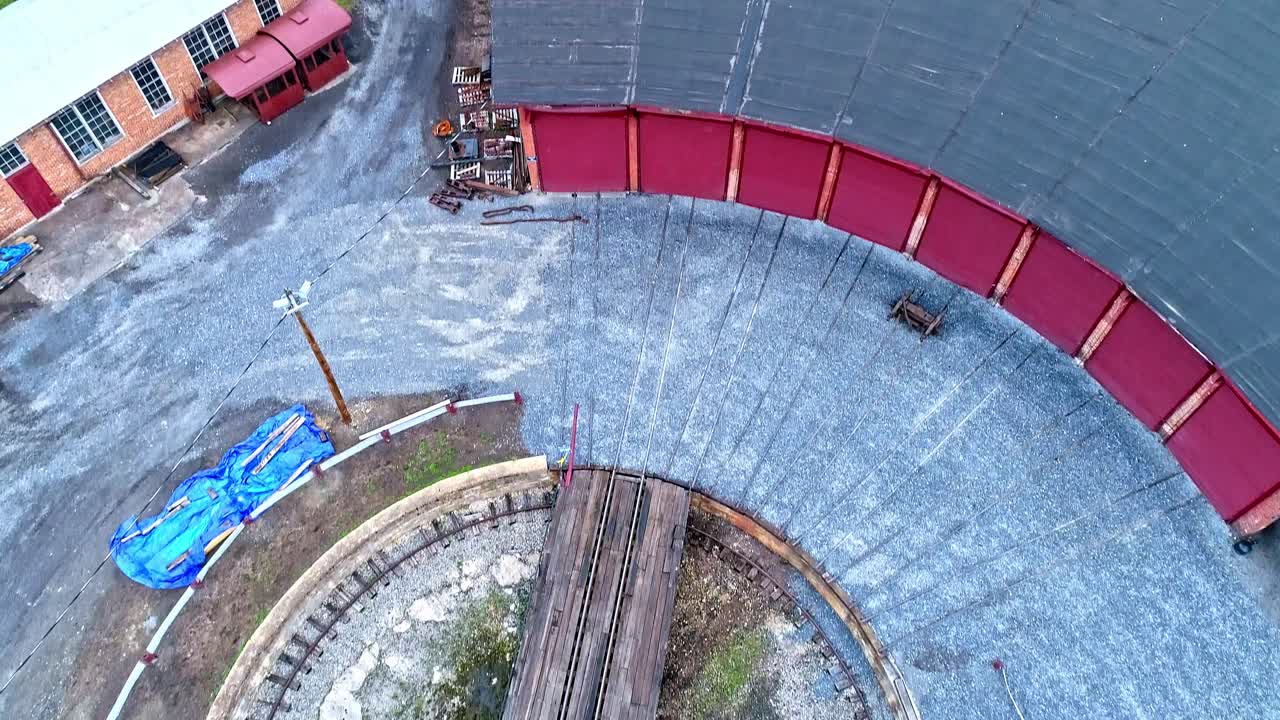 una vista aérea de una casa redonda de ferrocarril de carbón de vía estrecha abandonada y un edificio de soporte giratorio que comienza a restaurarse