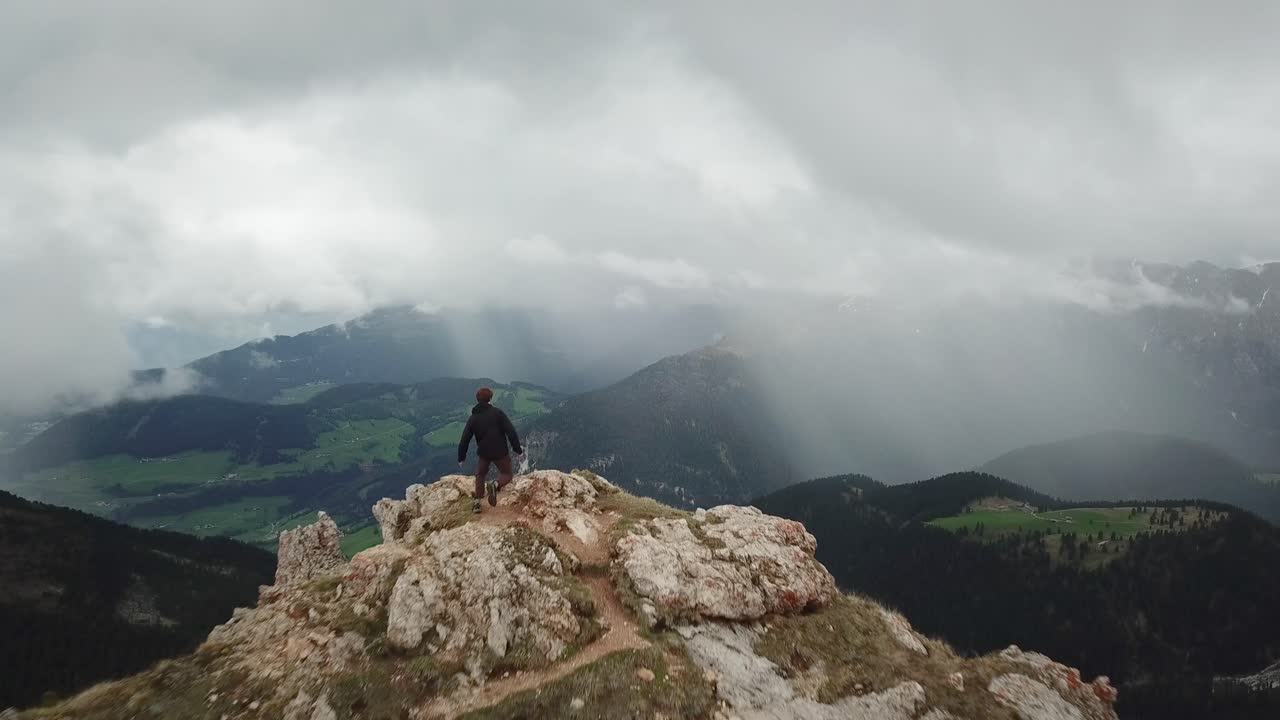 Drone shot passing by a running adventurer on top of a mountain to reveal Germany's beautiful countryside