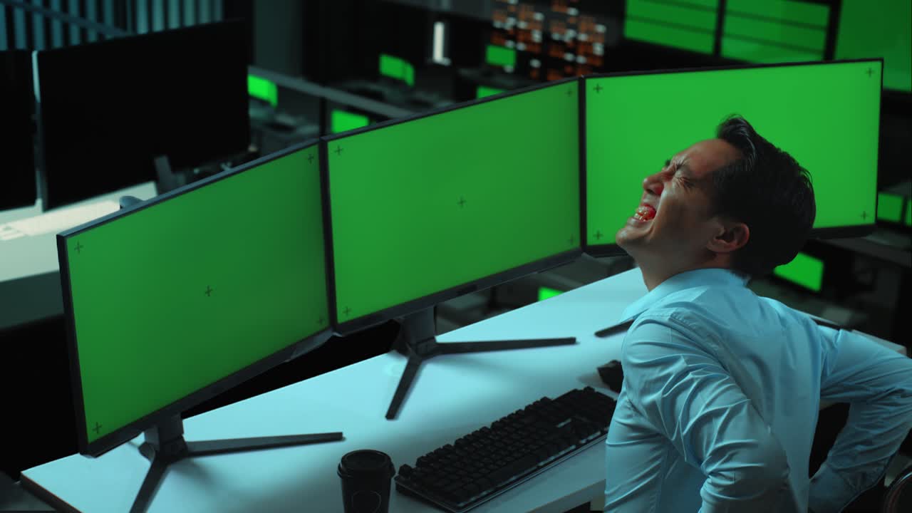 vista lateral de un hombre asiático con dolor de espalda mientras trabaja con múltiples monitores de computadora simulados en la oficina