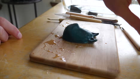 Ein-Kunststudent-In-Einem-Bildhaueratelier-Arbeitet-Mit-Nassem-Schleifpapier,-Um-Eine-Polymertonskulptur-Einer-Maskenfigur-Zu-Reinigen-Und-Zu-Polieren