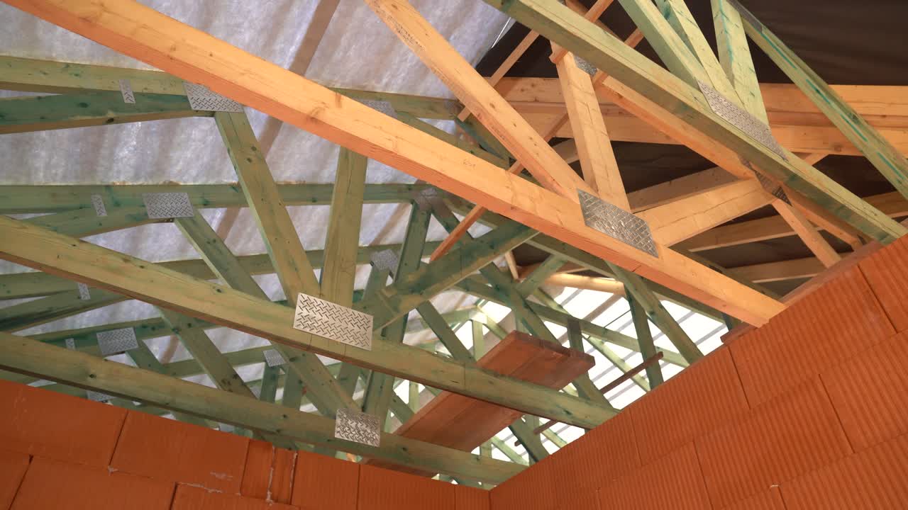 Wooden roof trusses and beams installed under membrane in unfinished brick house